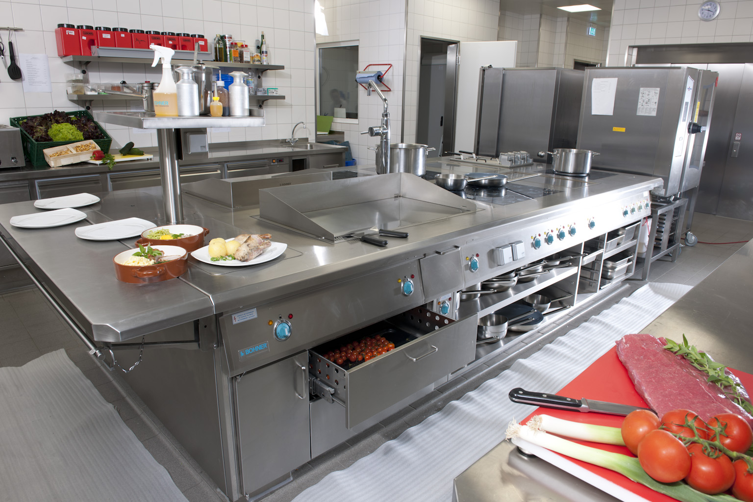 Blick in die Küche mit großem Herd und verschiedenen Küchenutensilien.