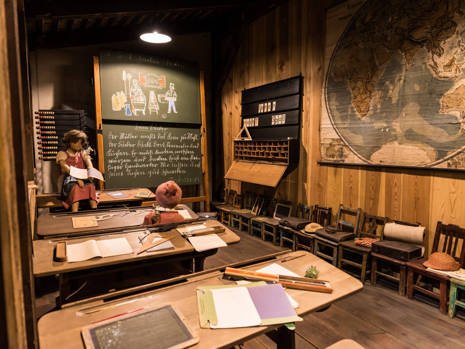 Ein Blick in die historische Schule mit alten Schulbänken und Stühlen und eine Schiefertafel.
