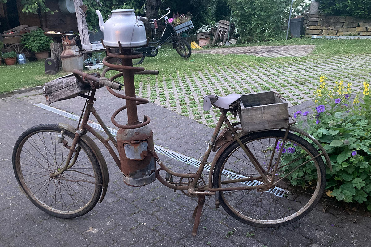 Ein Dampf-Fahrrad in Patina steht auf einem Hof.