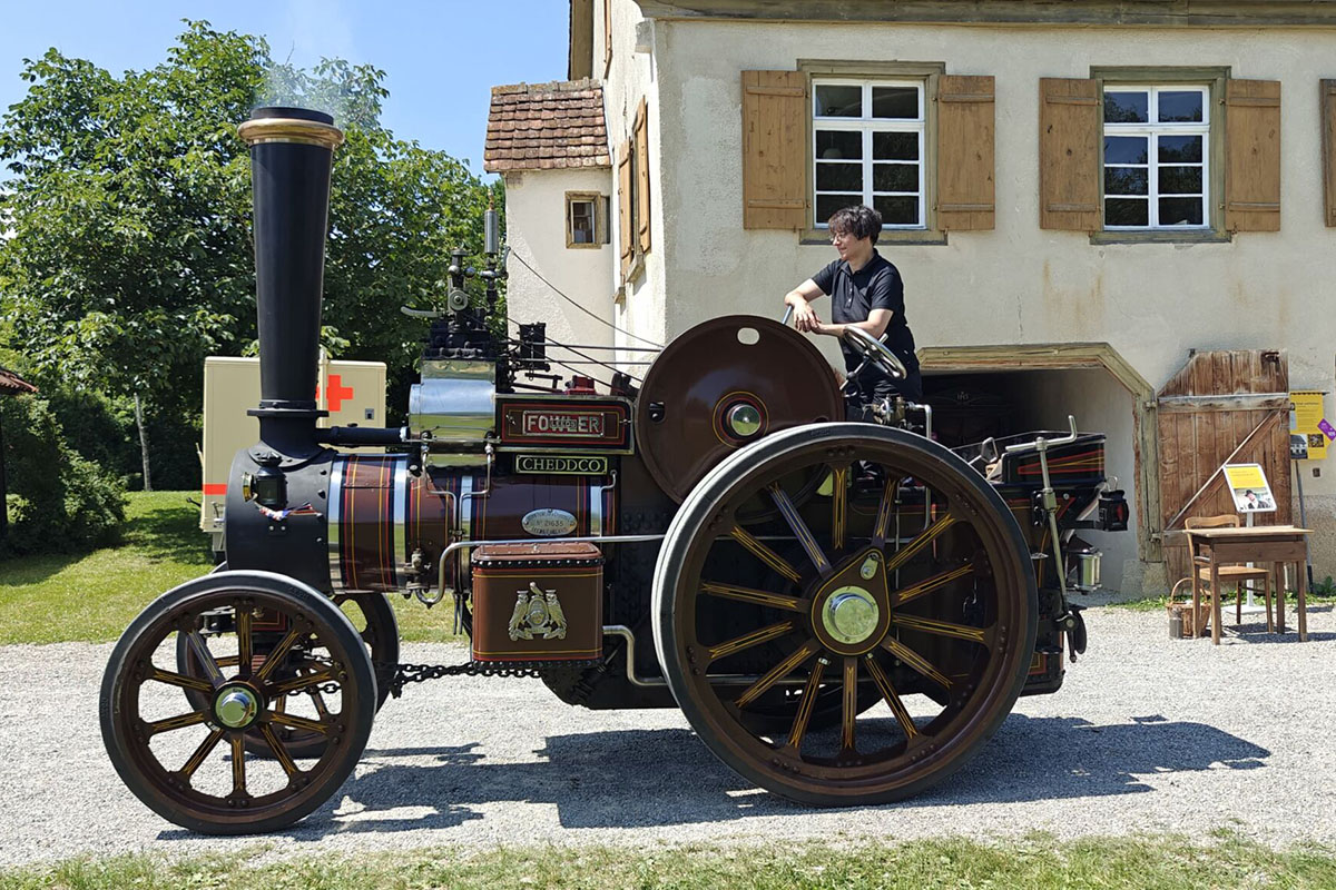 Dampftraktor T3B mit Baujahr 1938 steht auf dem Hof vor einem Haus.