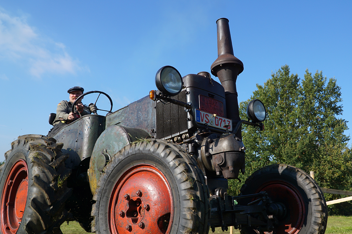 Lanz 1506 in Patina fährt auf einer Wiese.
