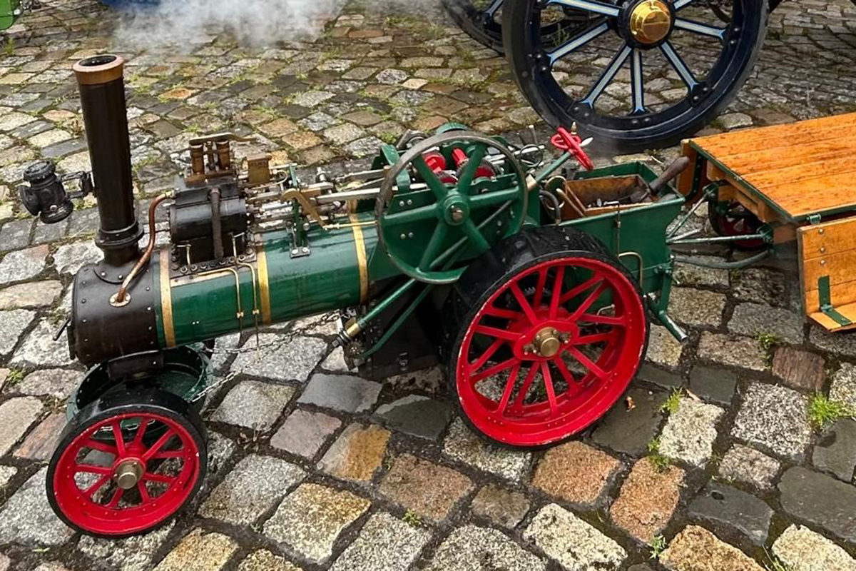 Ein Dampftraktor-Modell steht auf einem gepflasterten Platz.
