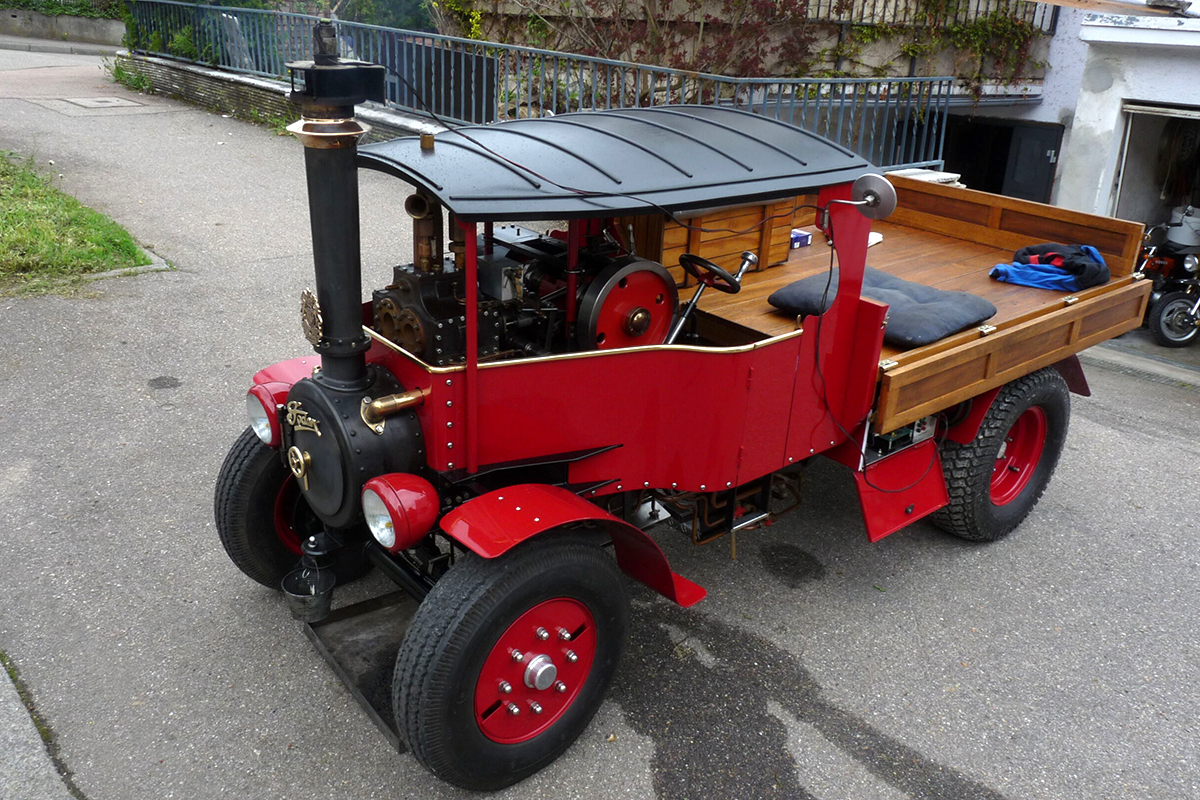 Ein roter Dampf-LKW steht auf einem geteerten Platz.