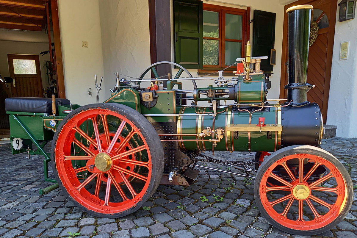 Ein Dampftraktormodell 4"scale, Typ 6NHP Agricultural Engine steht vor einem Haus.