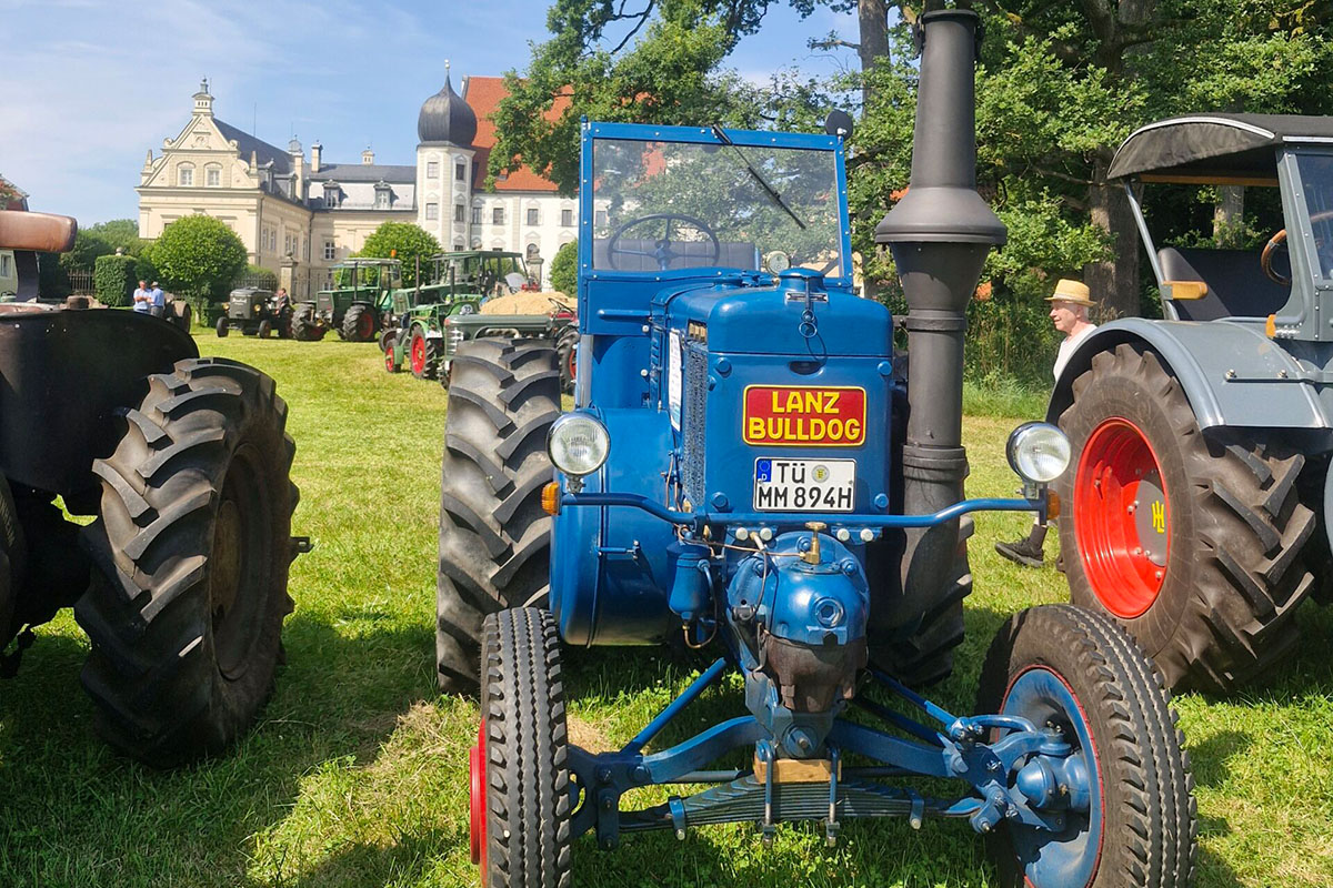 Ein blauer LANZ D9506 steht vor einem Schloss auf einer Wiese.
