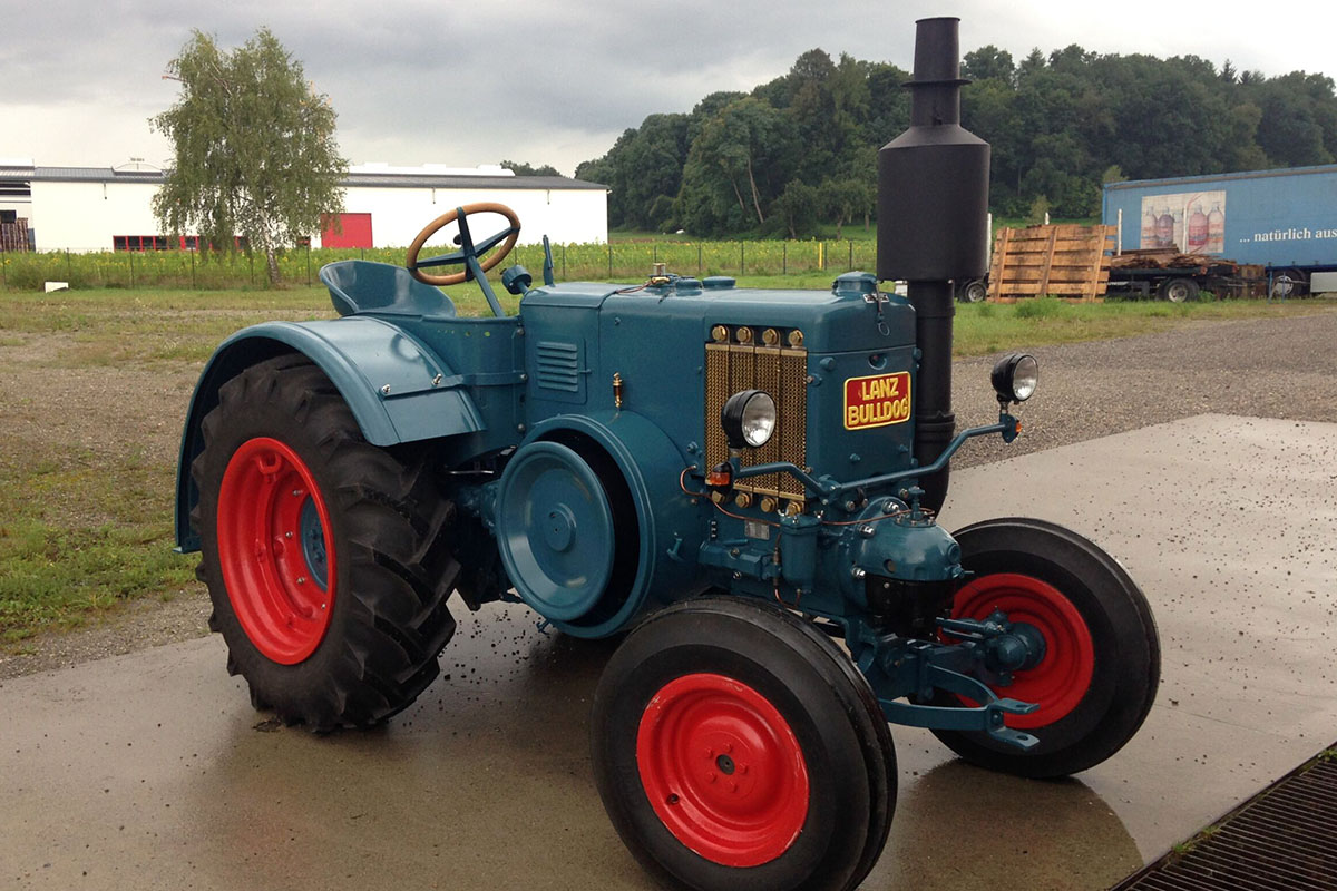 Ein Lanz D1516 steht auf einem geteerten Platz. Dahinter ist ein See.