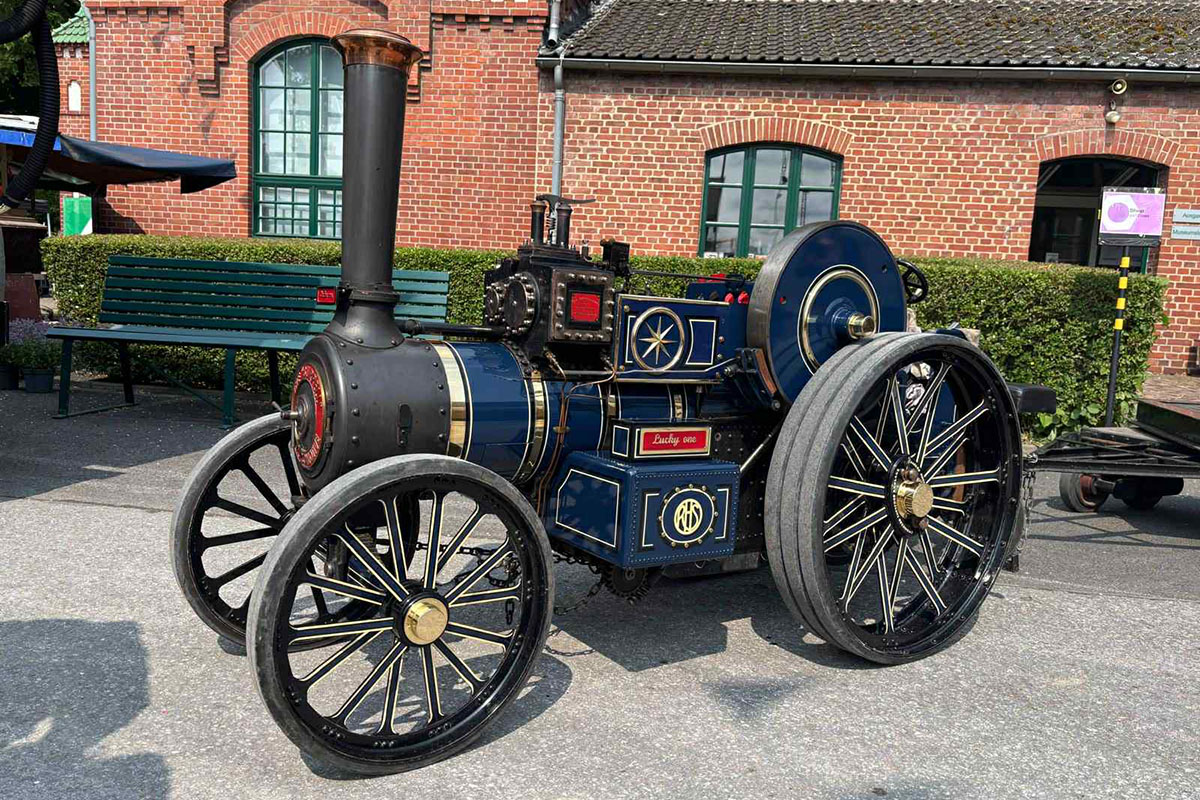 Eine Roadlocomotive steht vor einem Backsteinhaus.