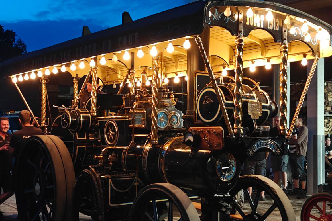 Eine mit Lichter bestückte Showmans Engine leuchtet bei Nacht.