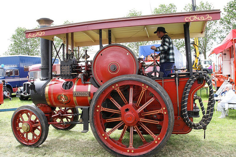 Ein roter Stoomtractor steht auf einer Wiese