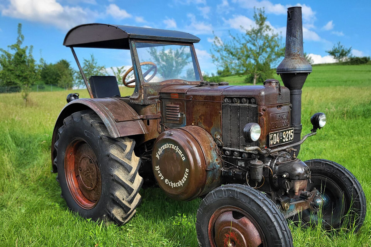 Ein Lanz D1506 in Patina steht auf einer Wiese.