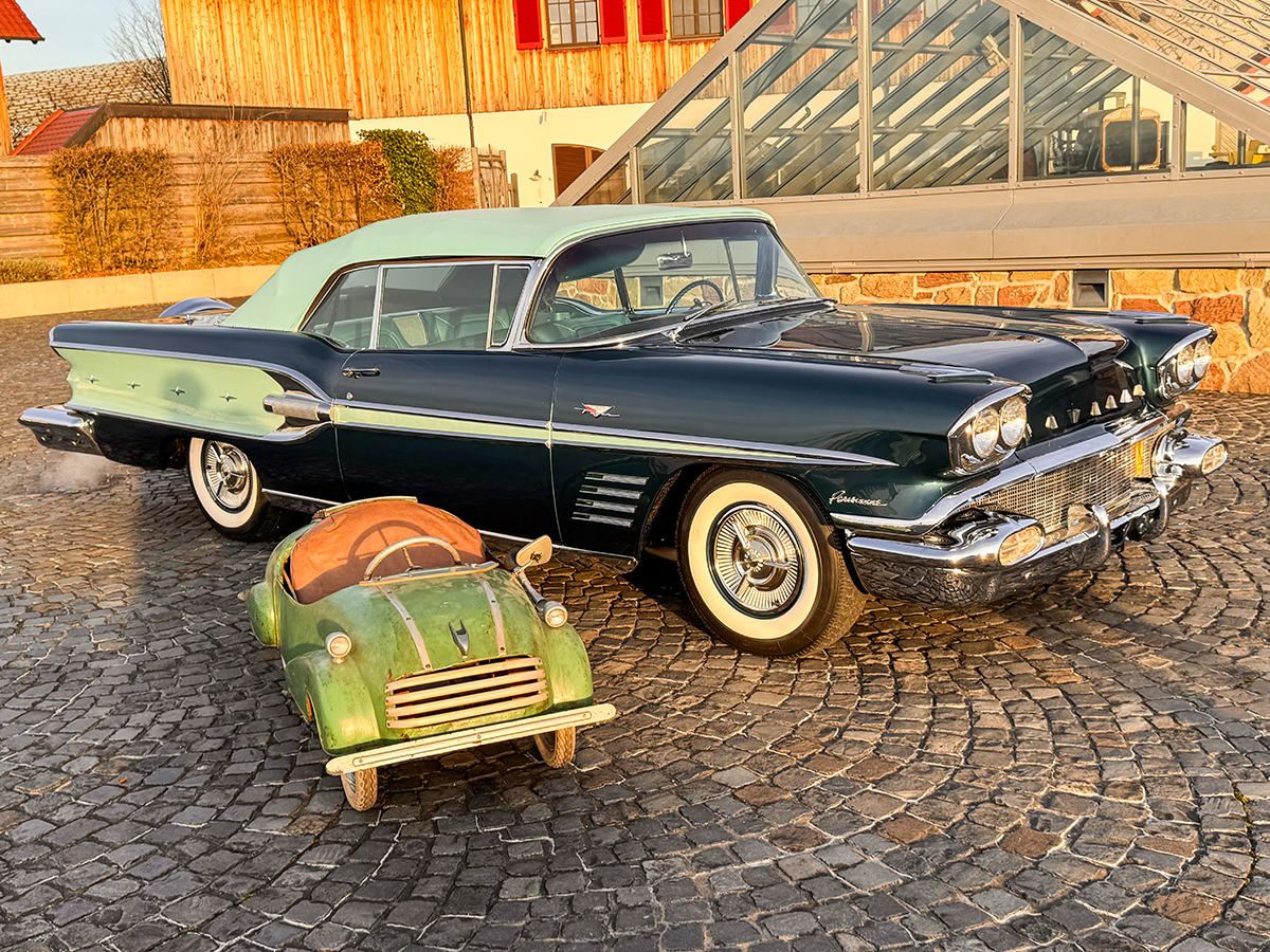 Ein blauer Pontiac mit einem kleinen grünen Kinderfahrzeug